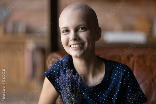 Foto Portrait of happy young hairless woman getting good result of treatment and chemotherapy, celebrating beating cancer, holding bouquet of fresh field flowers, looking at camera, smiling