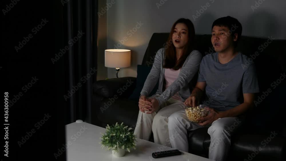 Crying young couple watching romantic movie TV on sofa at night Crying young couple watching romantic movie TV on sofa at night