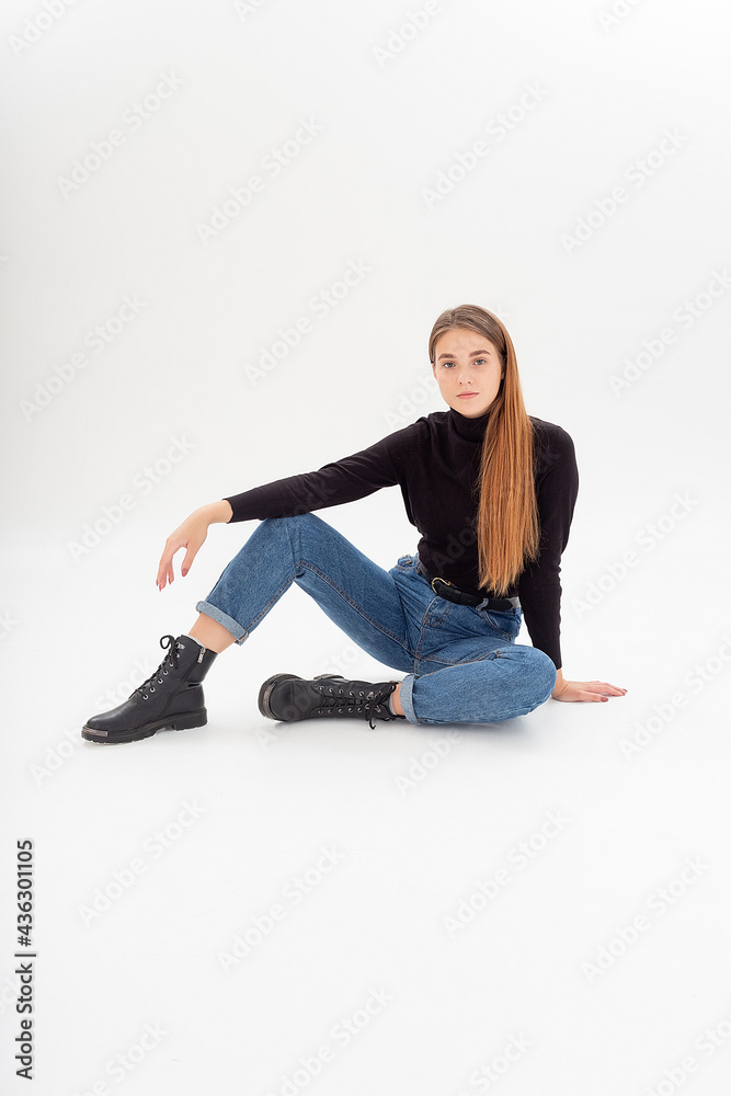 portrait of young attractive caucasian woman with long hair in black turtleneck, blue jeans isolated on white studio background. skinny pretty female sits on cyclorama. model tests of beautiful lady portrait of young attractive caucasian woman with long hair in black turtleneck, blue jeans isolated on white studio background. skinny pretty female sits on cyclorama. model tests of beautiful lady