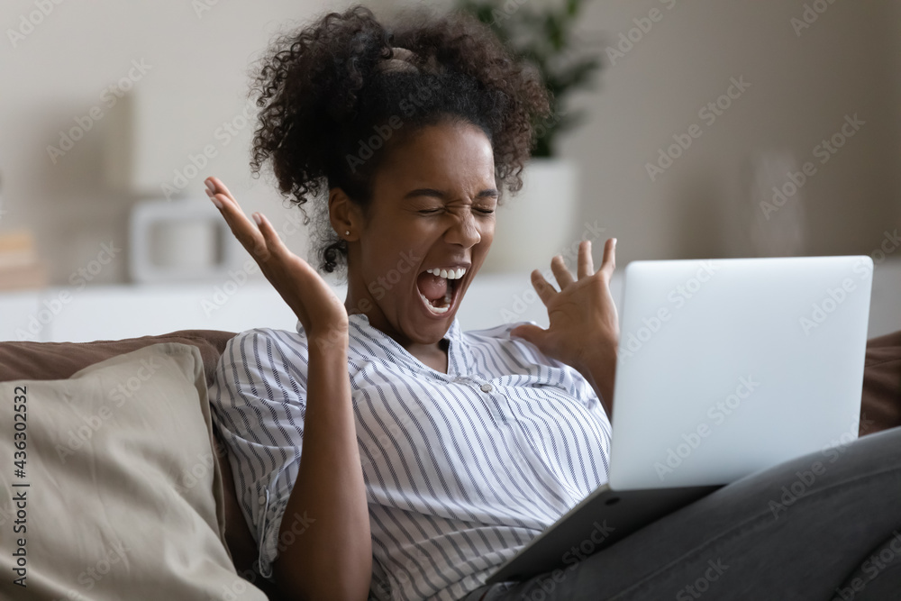 Overjoyed sincere young african american woman screaming, celebrating online lottery win, getting gambling auction giveaway victory email notification on computer, feeling happy alone at home. Overjoyed sincere young african american woman screaming, celebrating online lottery win, getting gambling auction giveaway victory email notification on computer, feeling happy alone at home.