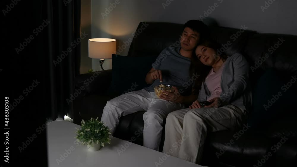 Happy young couple watching TV on sofa at night Happy young couple watching TV on sofa at night