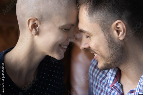 Romantic touch of foreheads of sweet young couple fighting against girlfriends cancer. Smiling faces of husband and wife talking close to each other. Love, intimacy, oncology concept. Close up