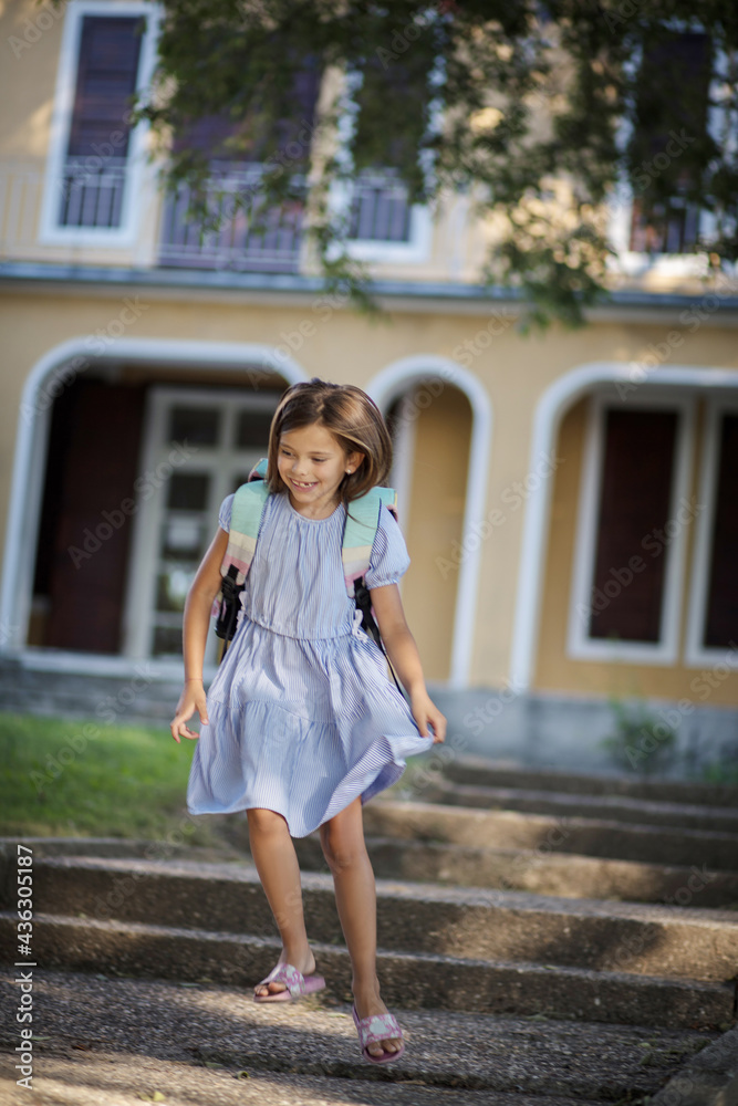 Little girl leaving school. Running and smiling. She goes home happy. Little girl with school bag.