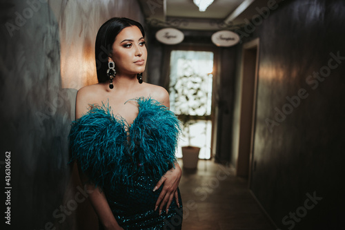 Shallow focusshot of a sexy Bosnian Caucasian woman wearing a blue-green dress, posing indoors photo