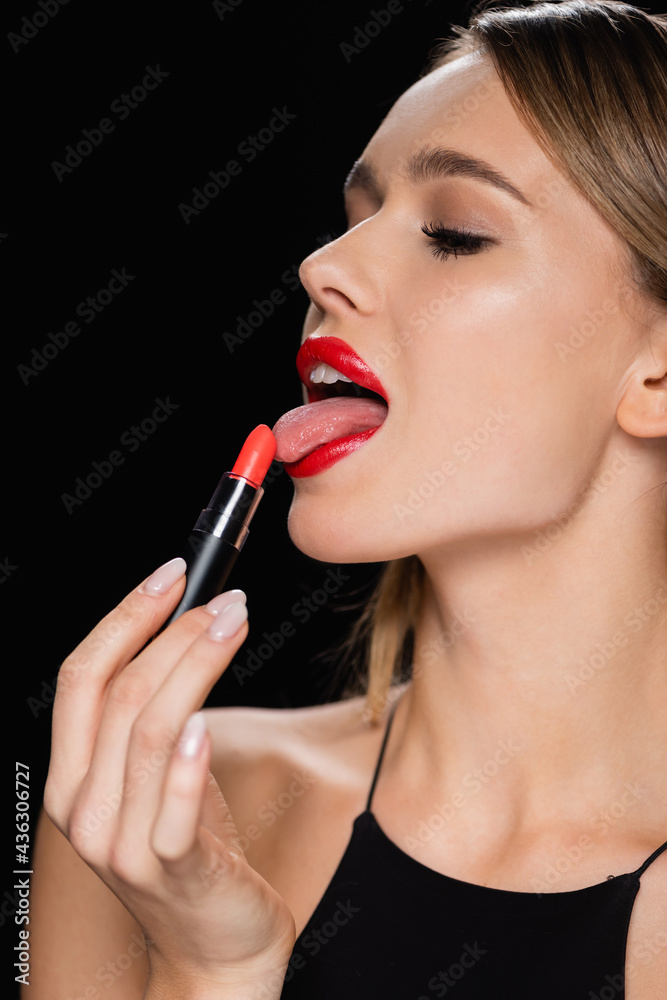 seductive woman licking red lipstick isolated on black. seductive woman licking red lipstick isolated on black.