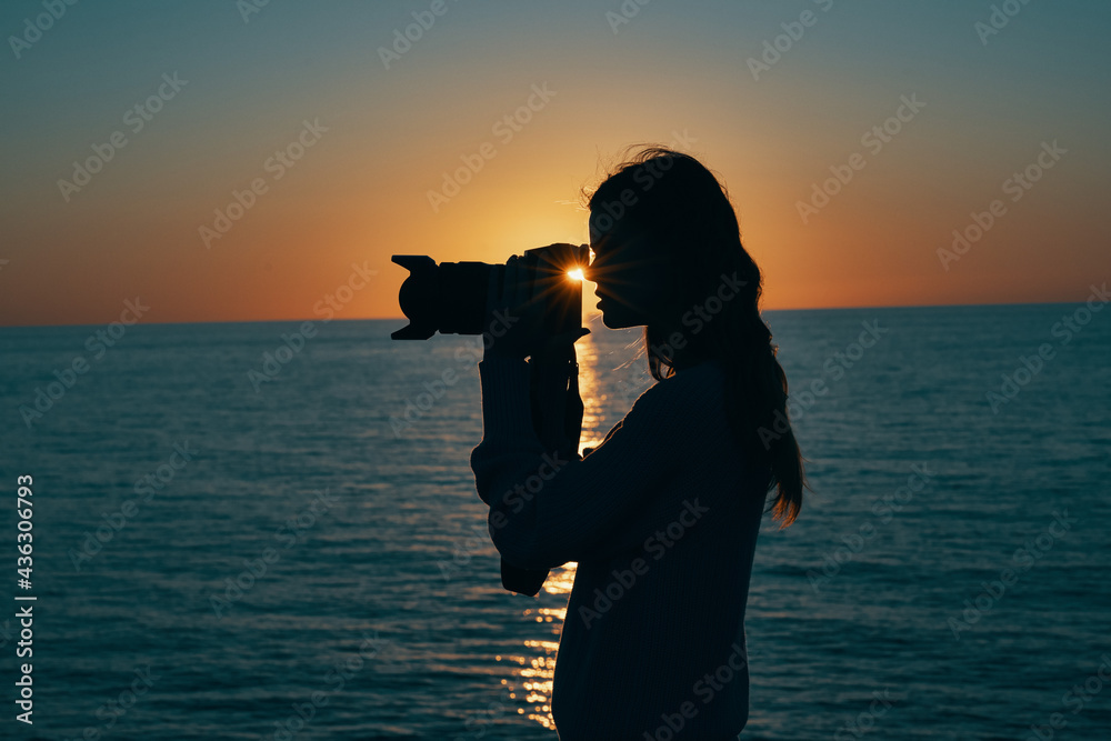 woman tourist holding professional camera on nature landscape sunset