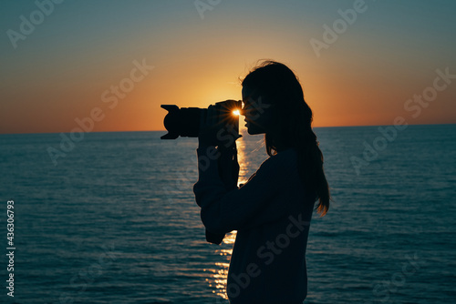 woman tourist holding professional camera on nature landscape sunset
