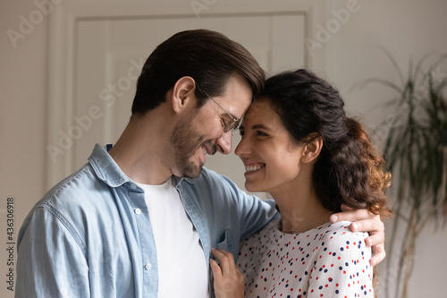 Bonding millennial married family couple touching foreheads, showing tender feelings at home. Loving caring young spouses cuddling, enjoying stress free peaceful weekend time together indoors. © fizkes