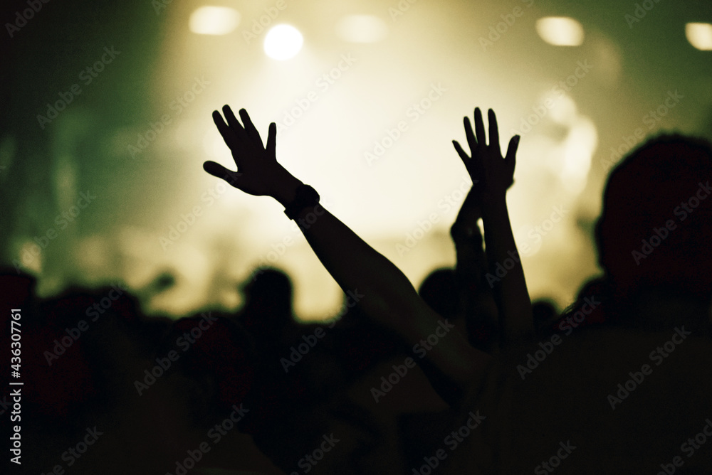 Crowd at a music concert, audience raising hands up, toned