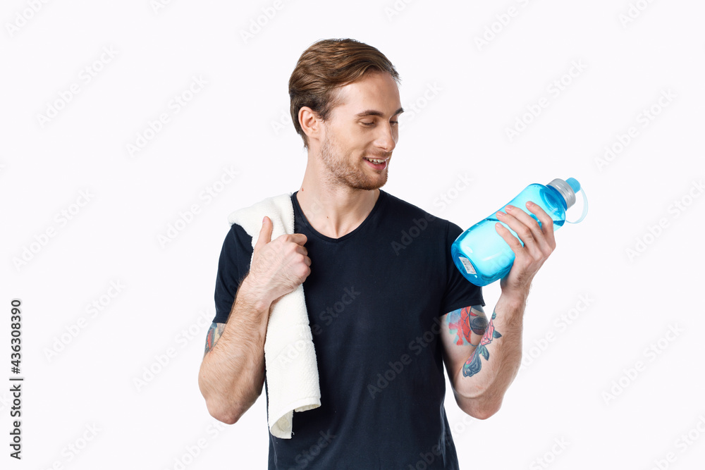 man in a black t-shirt with a bottle of water in his hand and a towel on his shoulder cropped view Copy Space man in a black t-shirt with a bottle of water in his hand and a towel on his shoulder cropped view Copy Space