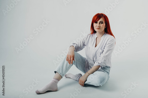 Portrait of a girl with bright red hair dressed in a light shirt. People and lifestyle concept. Copy space.