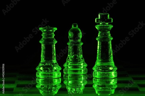 Piony szachowe szklane podświetlone na kolor zielony na czarnym tle