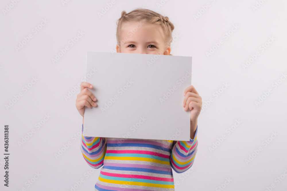 a happy cute little blonde girl with pigtails in a colored jacket holds a white sheet in her hands and smiles a happy cute little blonde girl with pigtails in a colored jacket holds a white sheet in her hands and smiles
