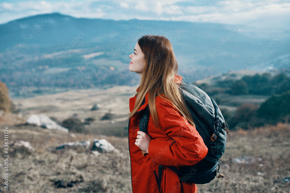 woman hiker in a jacket and with a backpack are resting in the mountains landscape Relax model woman hiker in a jacket and with a backpack are resting in the mountains landscape Relax model