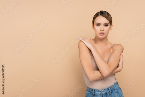 front view of sensual woman with perfect skin posing on beige.