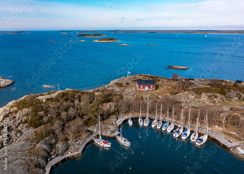 Small island with a sailboat harbor and a red cottage in Finland