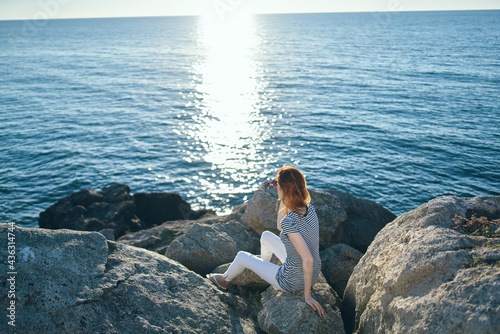 woman on the beach in the mountains on big stones sunset summer top view