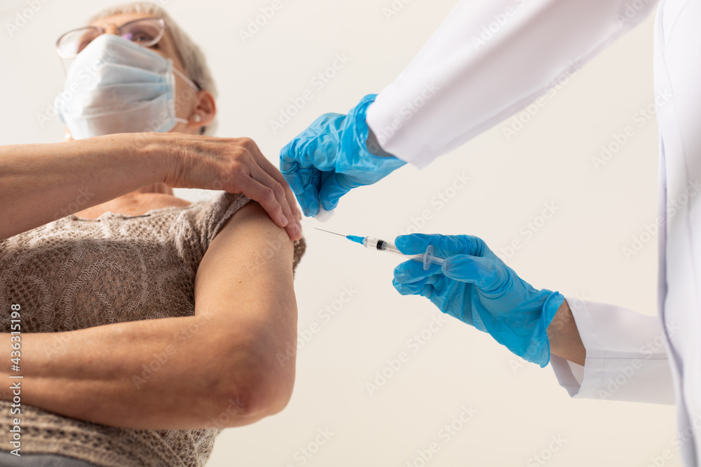 A doctor giving an injection of a covid-19 vaccine to an elderly patient.