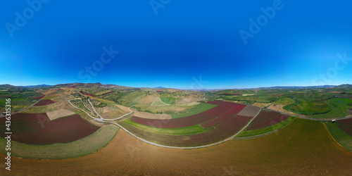 360 degree aerial photo of the red fields in the heart of Sicily in the Erei mountains. Sulla is a fodder for animals and is sown as bare seed on wheat stubble. Sicilian wheat with a view of Etna.