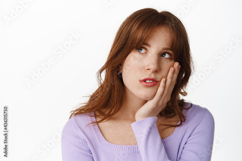 Gloomy and bored young woman roll eyes, staring at upper left corner with bored, uninterested face expression, tired of waiting, standing against white background