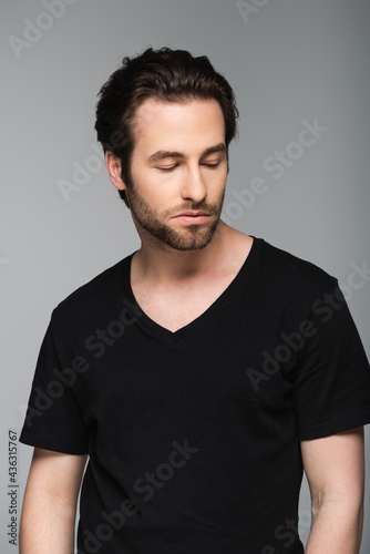 good-looking man in black t-shirt looking away while posing isolated on gray. © LIGHTFIELD STUDIOS