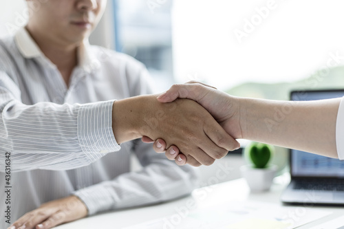 A close-up of a person shaking hands, two businessmen shaking hands after agreeing to sign a business investment contract together. The concept of a handshake to show universal reverence.
