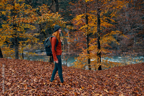 woman in autumn in the park with fallen leaves and a backpack on her back river in the background © SHOTPRIME STUDIO