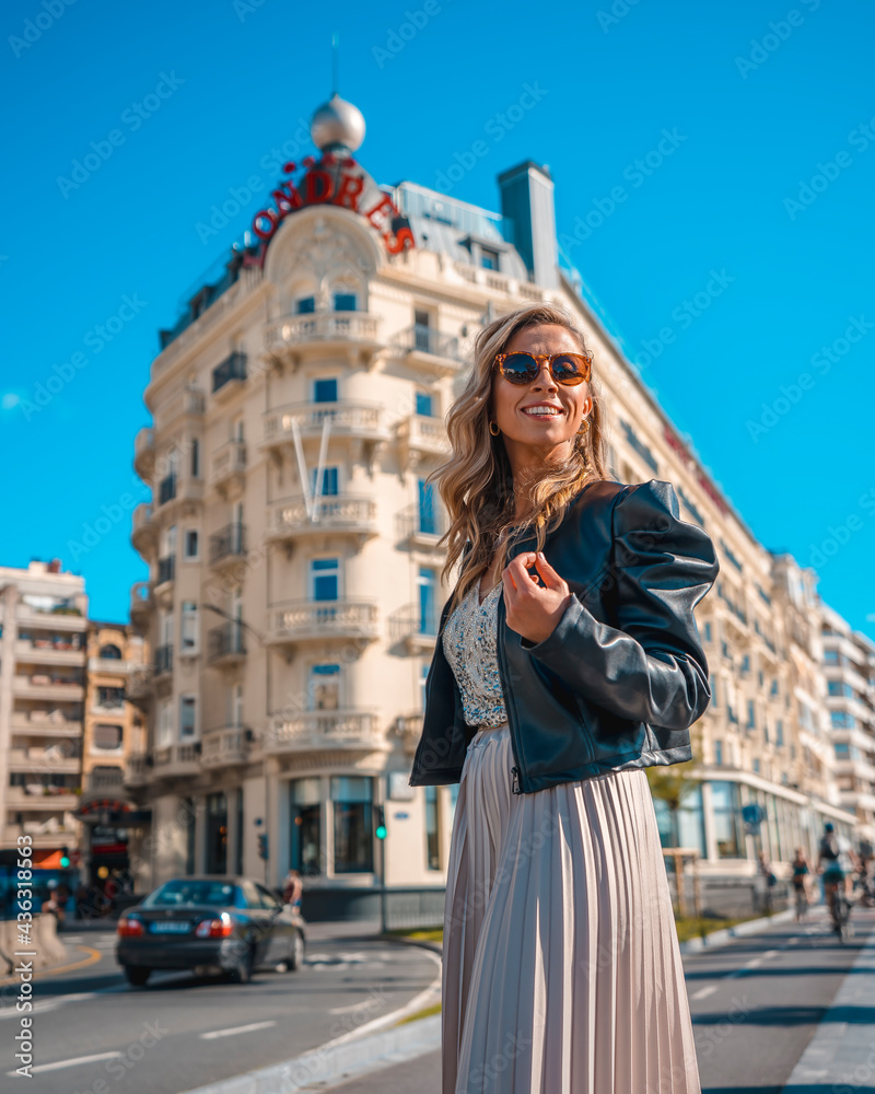 Gorgeous young blond Caucasian woman in an evening dress and a black leather jacket. Enjoying the holidays outside the hotel