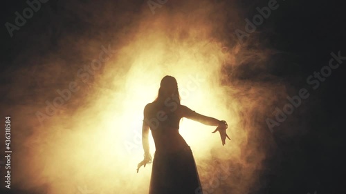 Woman dancing in smoke on a dark background