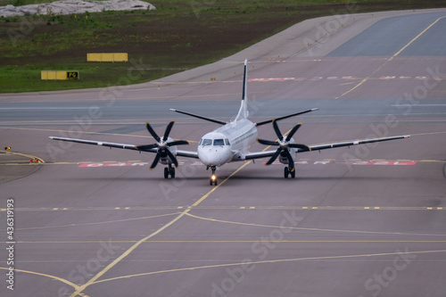 A white small turboprop airplane taxiing on the taxiway.