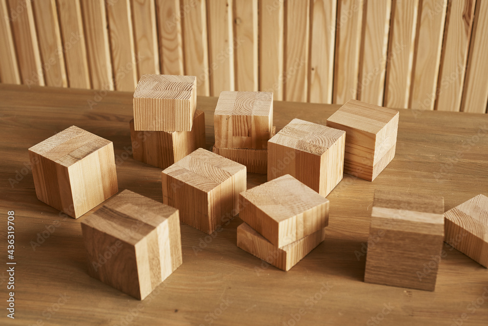 wooden cubes of different sizes lie on the table against the background of a wooden wall wooden cubes of different sizes lie on the table against the background of a wooden wall