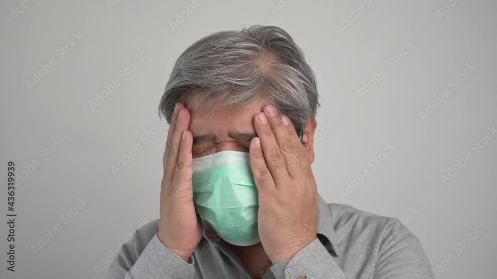 Sick Asian man wearing a medical face mask and Take a hand to hold the headache in the head. Concept of protection pandemic coronavirus and respiratory disease Sick Asian man wearing a medical face mask and Take a hand to hold the headache in the head. Concept of protection pandemic coronavirus and respiratory disease