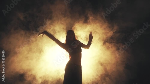 Woman dancing in smoke on a dark background