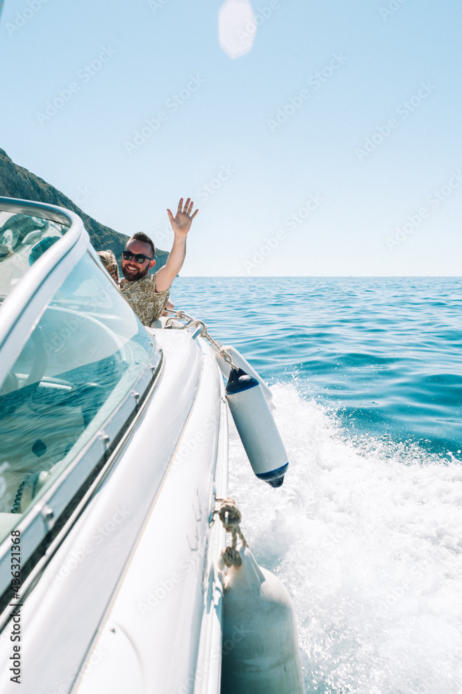 Naklejka premium Man waving hello from boat at the mediterranean sea