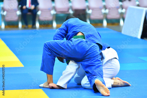 Two Boys judoka in kimono compete on the tatami 