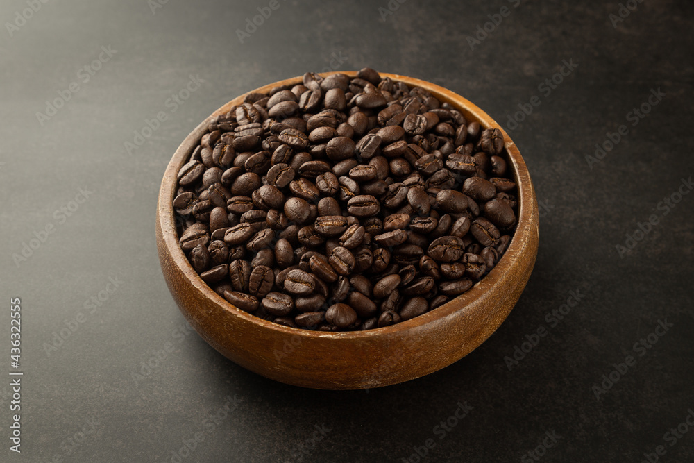 Fototapeta premium Coffee beans in wooden bowl on grunge background.