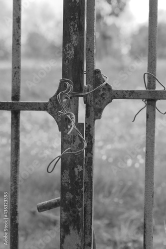 Fragment of an iron gate closed with an iron wire instead of a lock