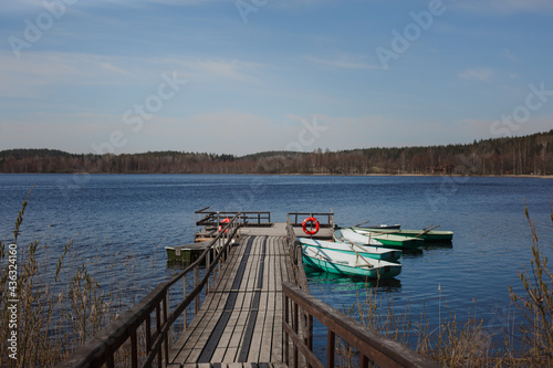 Empty old fishing boats with oars at the wooden pier. Lake with boats