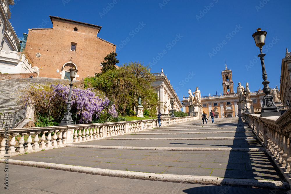 Rome, Italy, Piazza del Campidoglio. The imposing staircase leading to the Piazza del Michelangelo, the Capitoline Museums with the Statues of the Dioscuri, Cola di Rienzo in spring with the wisteria.
