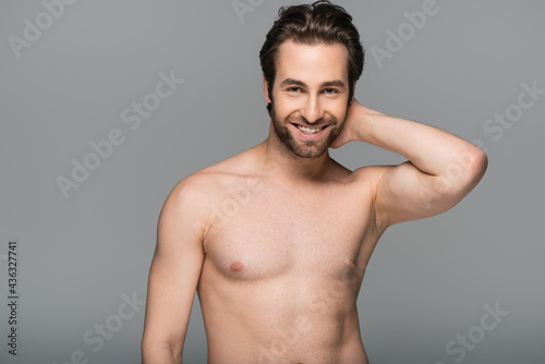 good-looking shirtless man smiling and looking at camera isolated on grey.