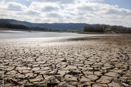 Closeup shot of cracks in the dry soil next to a drained pond