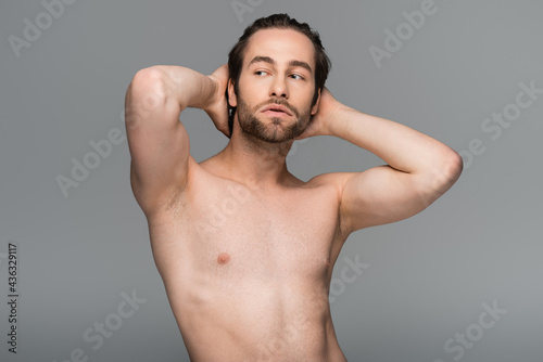 shirtless man posing while looking away isolated on grey.