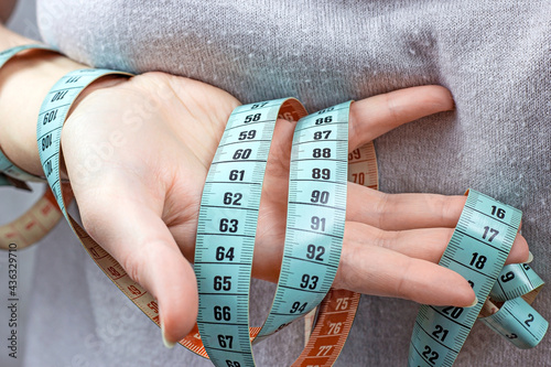 Caucasian woman hand holding the measuring tape with the 90-60-90 centimeters on it. The ideal woman figure and weightloss concept.