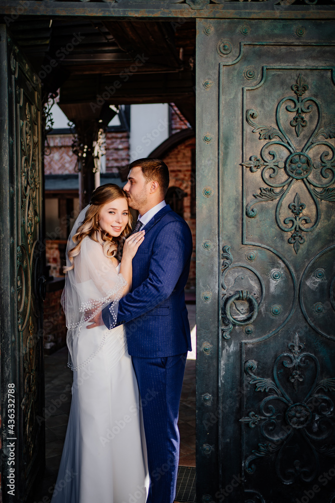 The bride and groom cuddle standing in the retro gate The bride and groom cuddle standing in the retro gate