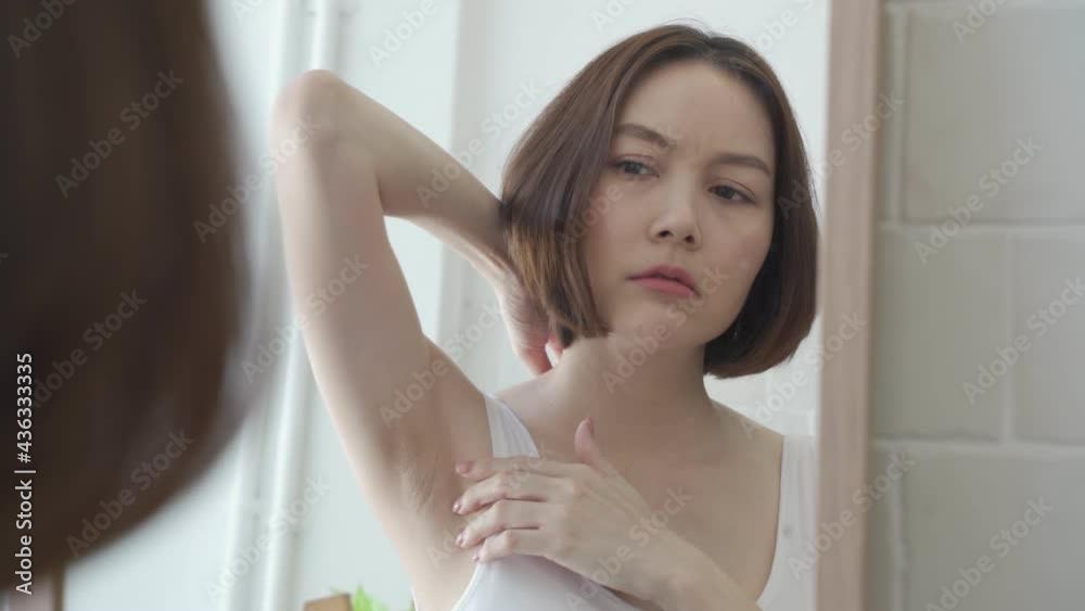 reflection mirror Asian female worry about black armpit with hair growing in bathroom at home. dark underarms concept. short hair woman looking mirror concern worried and Lack of confidence. problem.