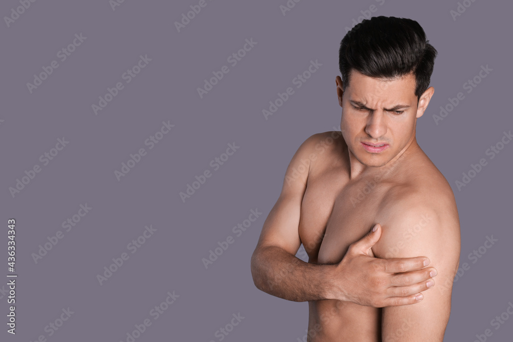 Man suffering from shoulder pain on grey background. Space for text Man suffering from shoulder pain on grey background. Space for text
