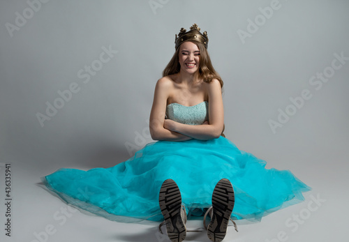 Modern princess, beauty in a crown and a lush blue dress and sneakers,