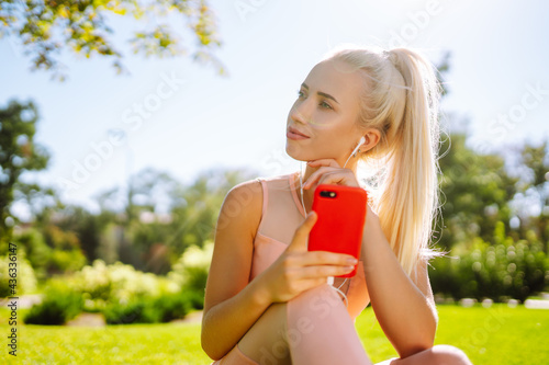 Young yoga woman enjoy listening to music with headphone with feeling happy and relaxed in the park. Summer holidays, sport, vacation and lifestyle.