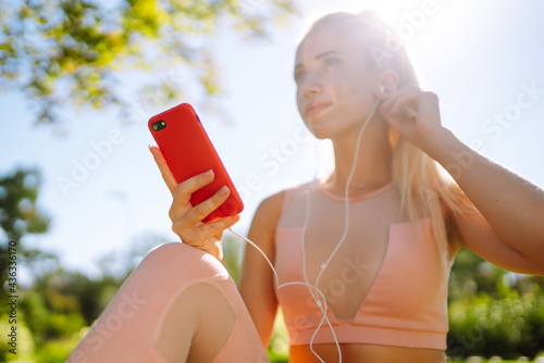 Young yoga woman enjoy listening to music with headphone with feeling happy and relaxed in the park. Summer holidays, sport, vacation and lifestyle.