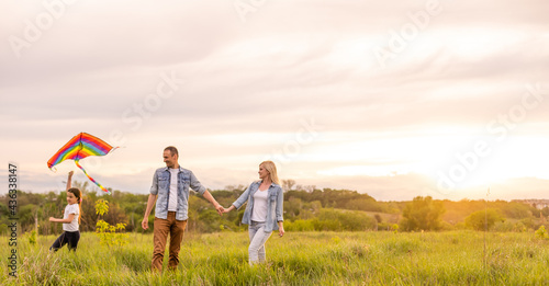 Happy family: mother, father, child daughter on nature on sunset.